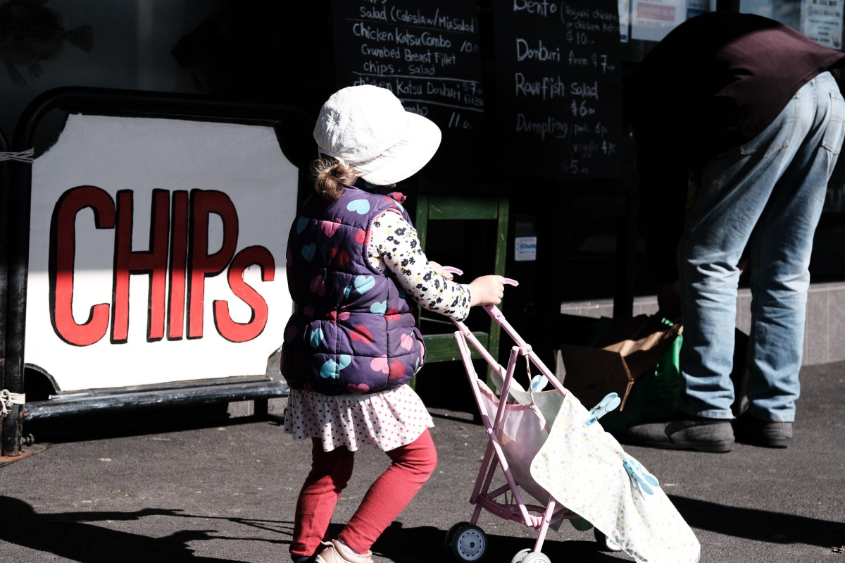 Little girl walking past a fish chips shop